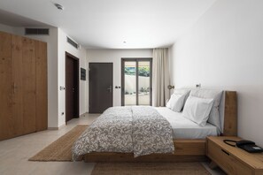 Une chambre à coucher comprenant un lit, une table de chevet, une armoire et une porte-fenêtre coulissante donnant sur un espace extérieur.