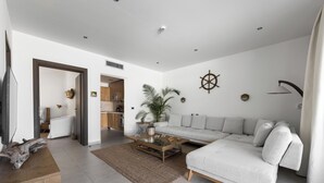 Un salon moderne avec un canapé d’angle, une table basse, un téléviseur et un mur décoratif.