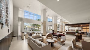 Eine großzügige Lobby mit einer großen Couch, Sesseln, einem Couchtisch und einer Rezeption.
