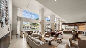 Um hall amplo com um sofá grande, poltronas, uma mesa de centro e um balcão de recepção.