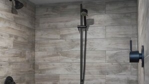 Une douche équipée d’un pommeau de douche à main et d’un robinet fixé au mur.