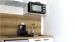 A compact kitchenette with a microwave, coffee maker, and a small refrigerator. - HOTEL ARCHIPEL (Balaruc-les-Bains)