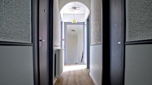 A narrow hallway with wooden flooring, white walls, and dark doors. - HOTEL ARCHIPEL (Balaruc-les-Bains)