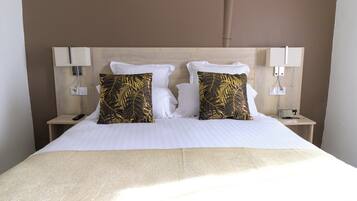 A hotel room with a bed, two nightstands, a lamp, and a power outlet on each side.