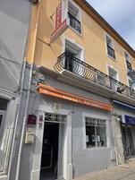 Un hotel con un letrero que dice 'HOTEL ARCHIPEL', un balcón con barandillas de metal ornamentadas y una puerta con un letrero que indica 'HOTEL ARCHIPEL'.