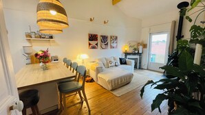 A cozy living room with a dining area, wooden flooring, a large plant, and a fireplace. - Charming family apartment in Basque house 10 minutes from beaches (Anglet)