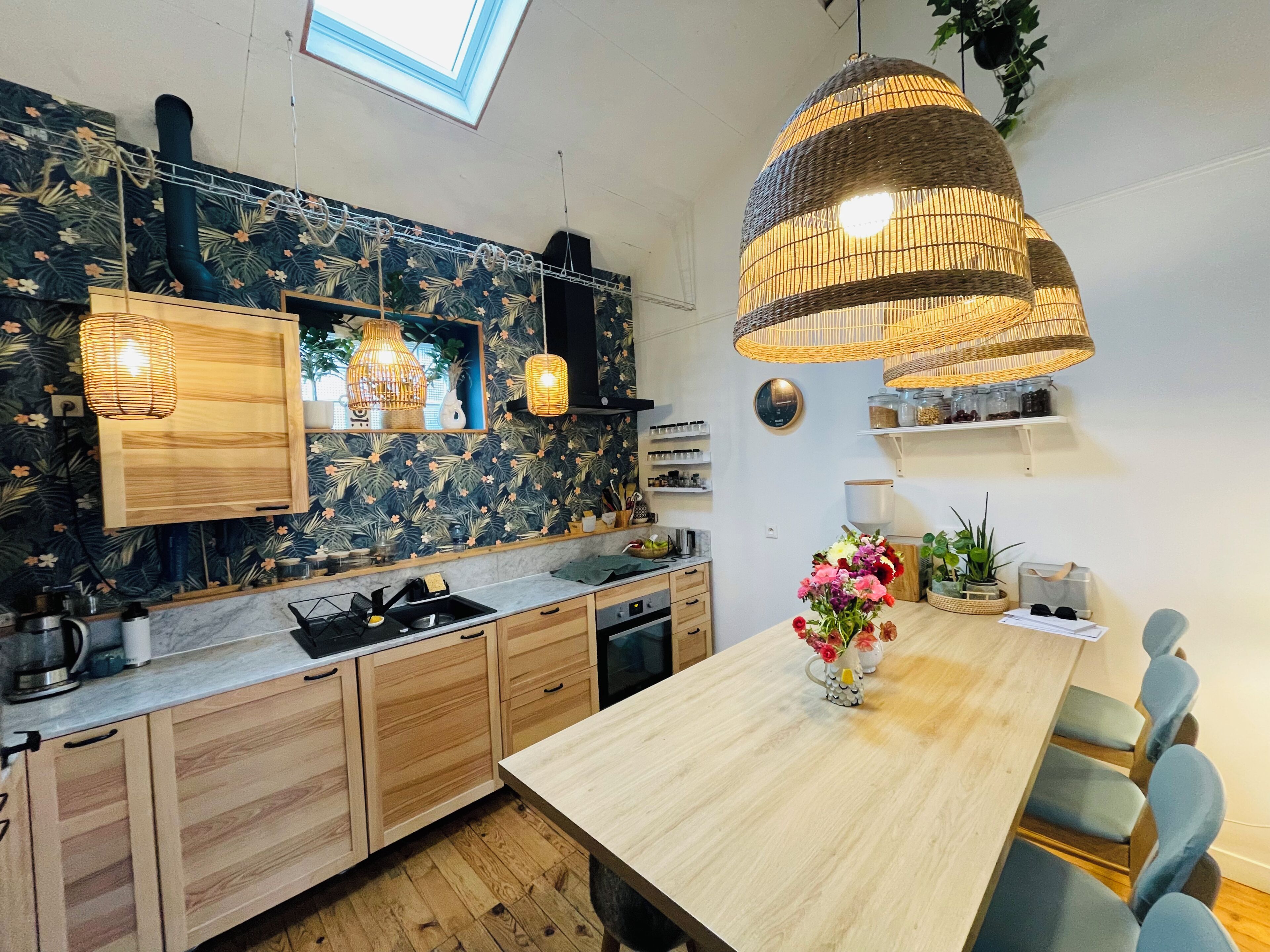 Une cuisine moderne avec des meubles en bois, un plan de travail en marbre et un coin repas comprenant une table en bois et des chaises bleues.