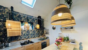 A modern kitchen with wooden cabinets, a marble countertop, and a dining area with a wooden table and blue chairs.