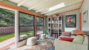 Una habitación con un ventanal amplio, una estantería, un sofá y un cuadro.