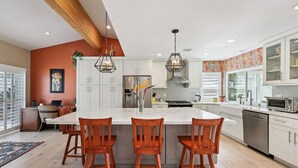 Una cocina moderna con una isla grande, armarios blancos y sillas de madera.