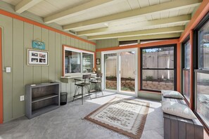 A kitchen with a built-in oven, a dining area with chairs, a bench, and a large sliding glass door leading to a backyard. - South Oceanside Retreat 1.3 miles to the Beach! (Oceanside)