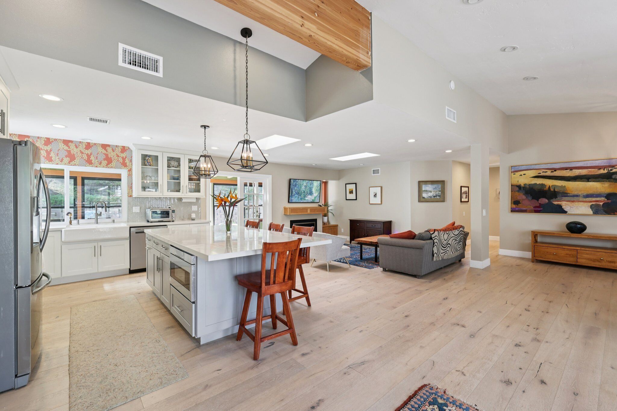 A spacious kitchen with a central island, wooden ceiling, and modern lighting.