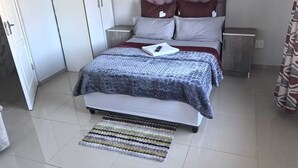 Ein Schlafzimmer mit einem Bett, Nachttischen, einem Kleiderschrank und einem gemusterten Teppich.