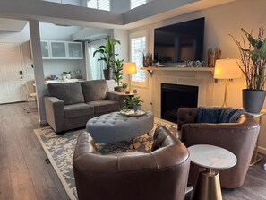 A modern living room with a fireplace, leather furniture, and a flat-screen TV. - California Dream Beach House - Harbor Pointe (Carlsbad)