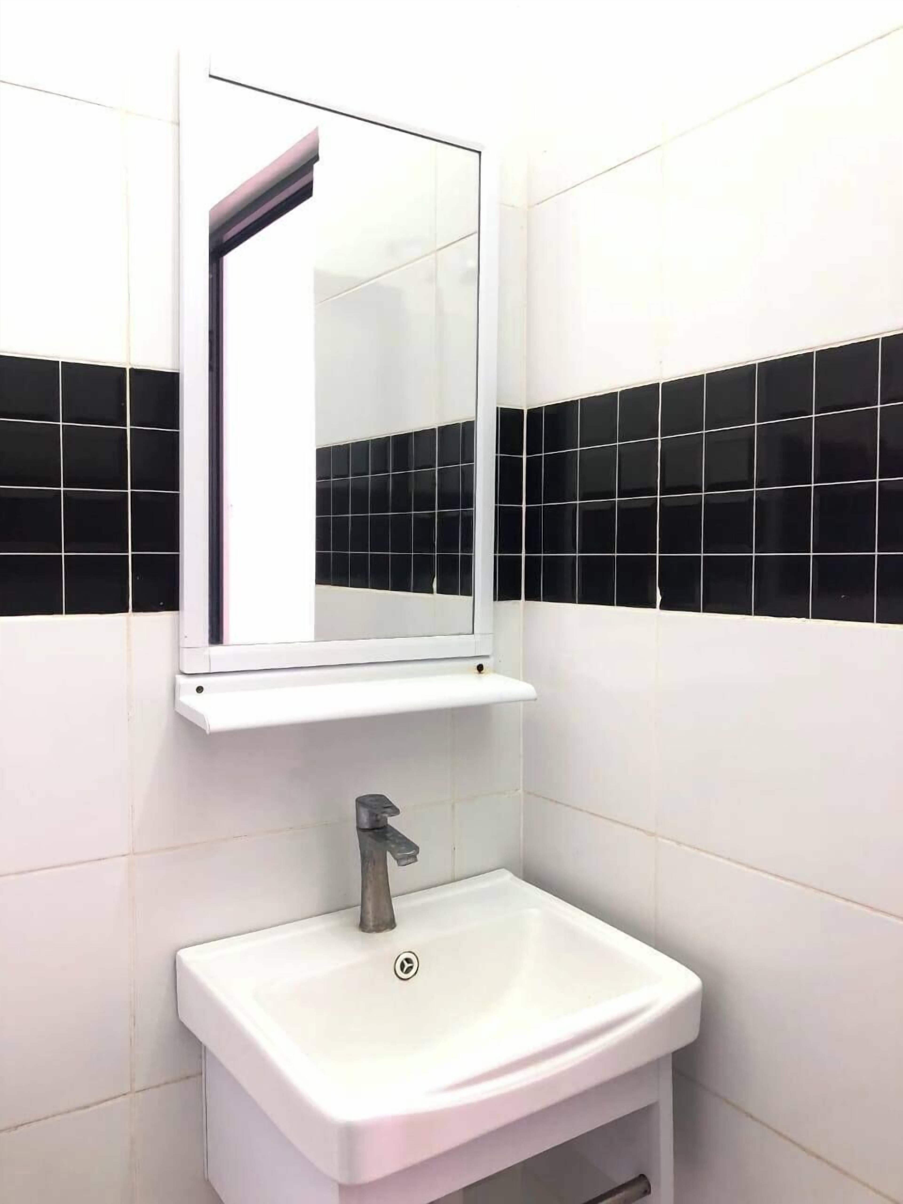 A bathroom with a white sink, a mirror, and black-tiled walls.