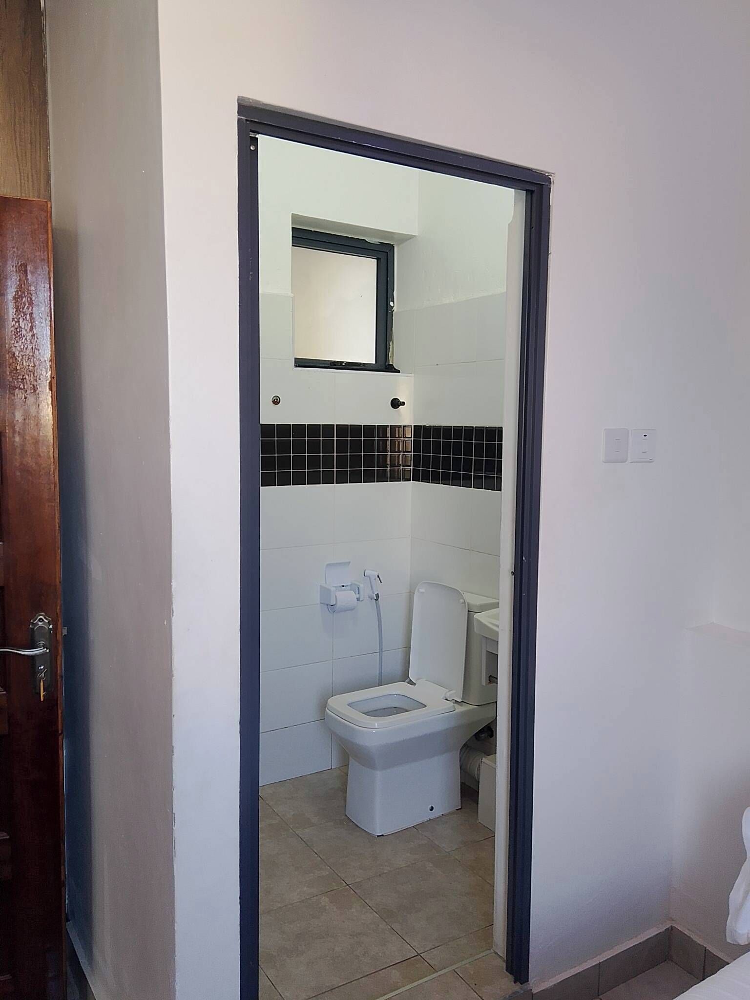 A bathroom with a toilet, a mirror, and a towel rack.