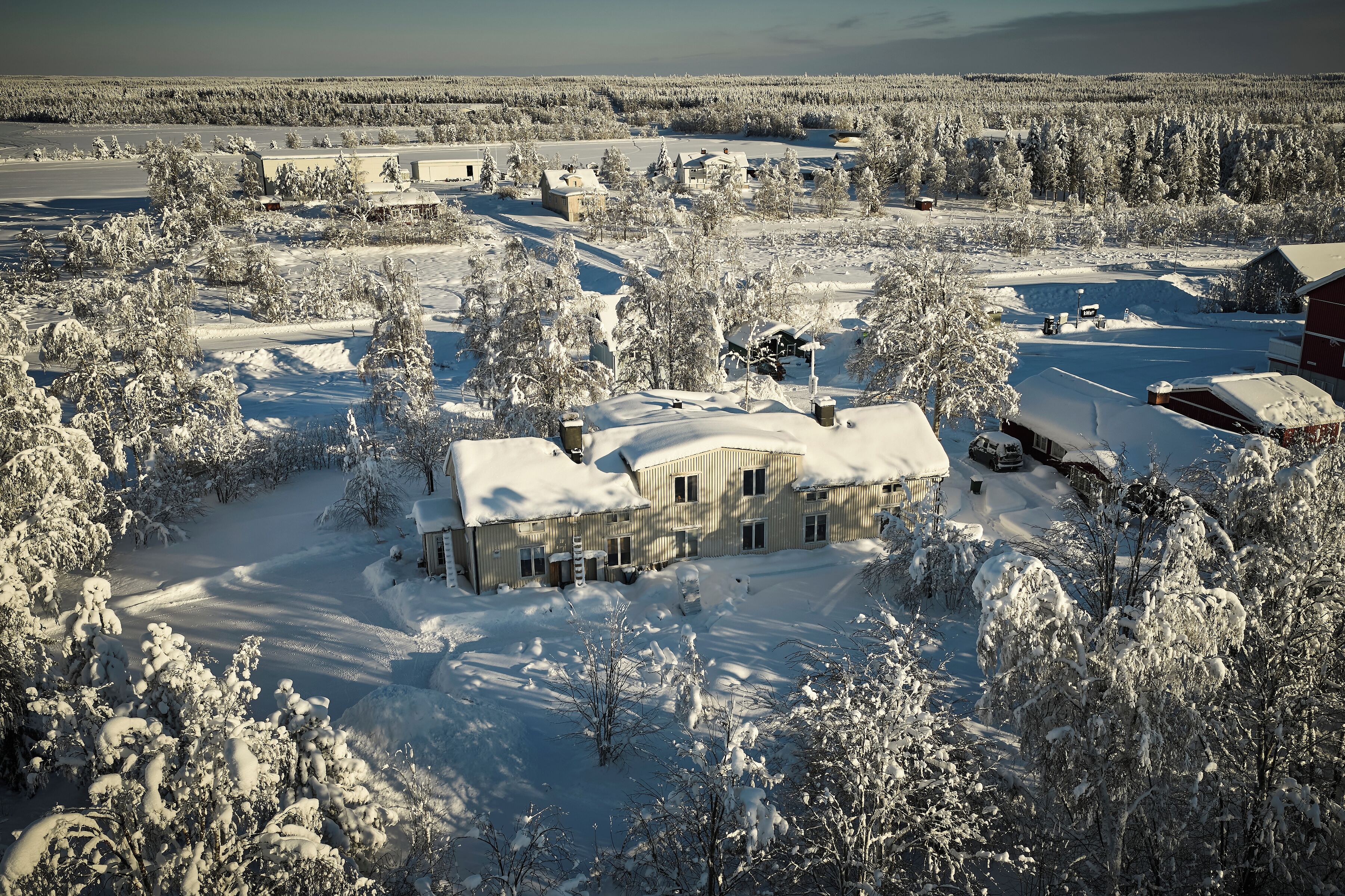 A large house surrounded by snow-covered trees and a clear sky.