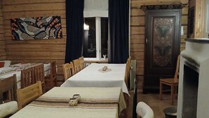 Ein Essbereich mit einem langen Tisch, Stühlen, einem Bild an der Wand und einem Kamin.