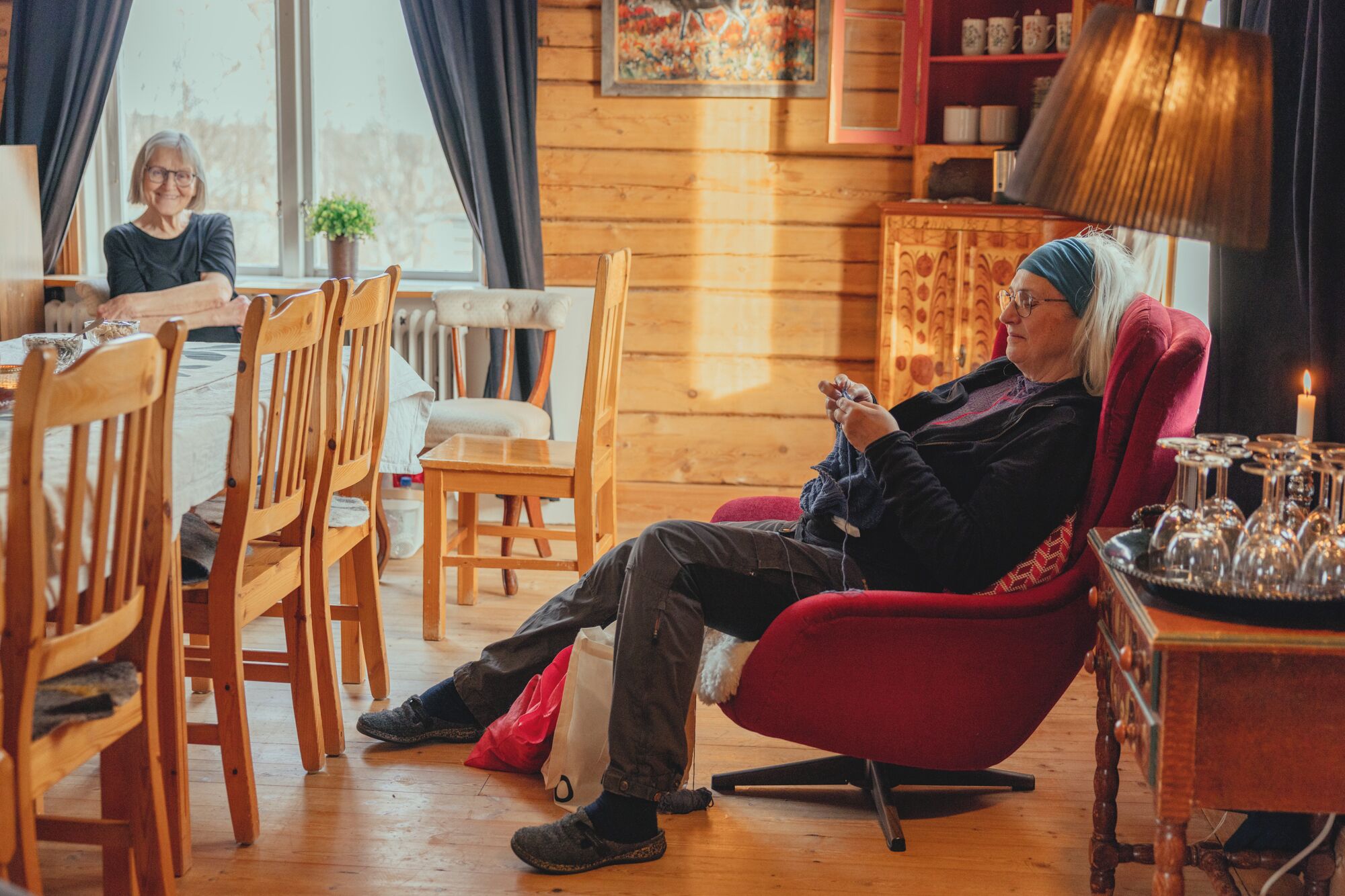Een gezellige kamer met houten meubels, een rode fauteuil en een eethoek met stoelen en een tafel.