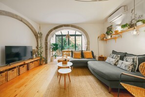Een woonkamer met een bank, televisie en een eethoek met een tafel en stoelen.