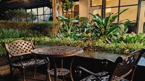 An outdoor seating area with a round table and chairs, surrounded by greenery and a building in the background. - Barefoot Sanctuary Stylish Condo Perfect for Staycations (Makati)