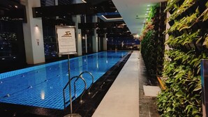 An indoor swimming pool with a sign, a tiled floor, and a wall with greenery. - Barefoot Sanctuary Stylish Condo Perfect for Staycations (Makati)