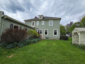 A two-story house with a front yard, a small garden, and a wooden structure. - The Marr House on the River (Greene)