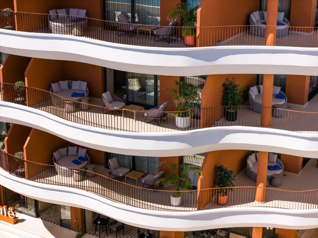 Ein mehrstöckiges Hotel mit Balkonen, Außenbereich und Blumentöpfen.