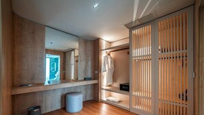 Un baño moderno con suelo de madera, un espejo, un perchero y un mueble de almacenamiento con puerta corredera.