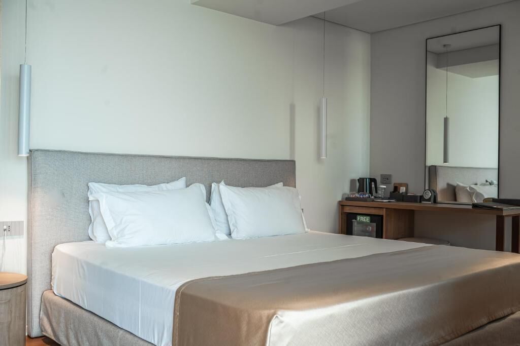 Une chambre d’hôtel avec un lit, une table de chevet et un miroir.