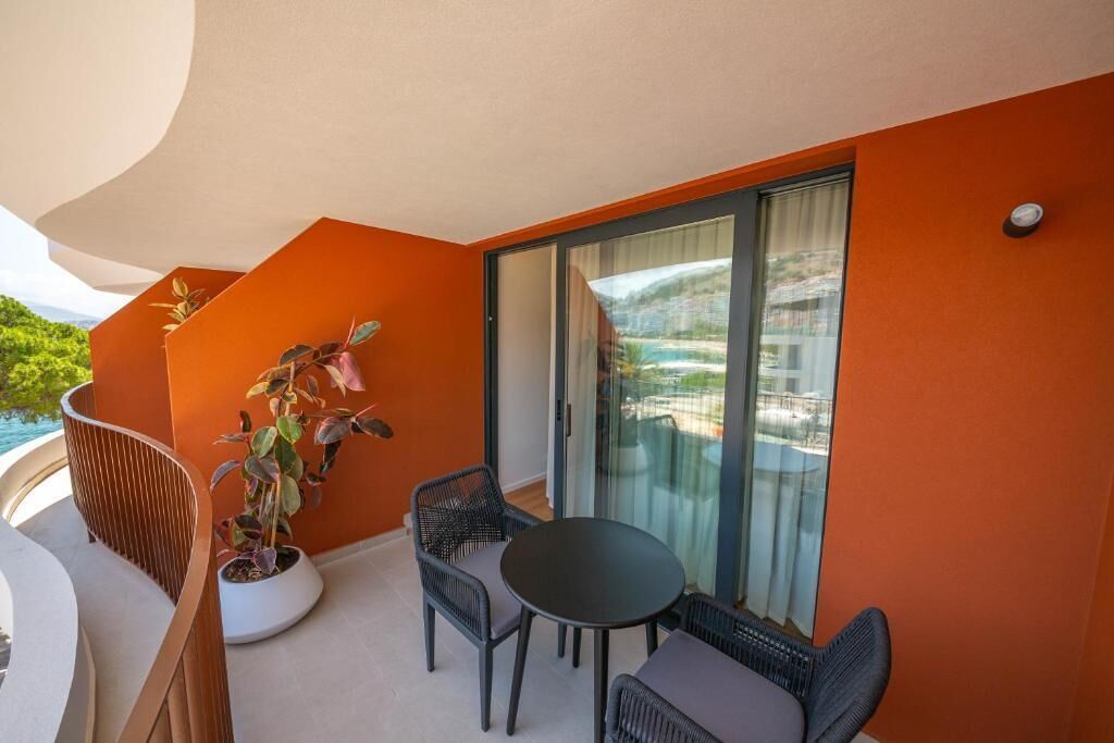 A balcony with a potted plant, two chairs, and a table.
