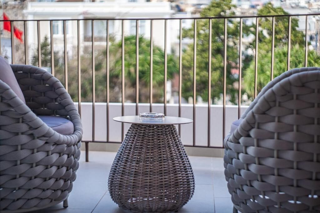 A balcony with wicker furniture and a small table.