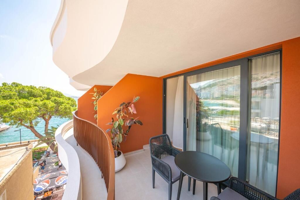 Ein Balkon mit Tisch und Stühlen, einem Blumentopf und Blick auf das Meer.