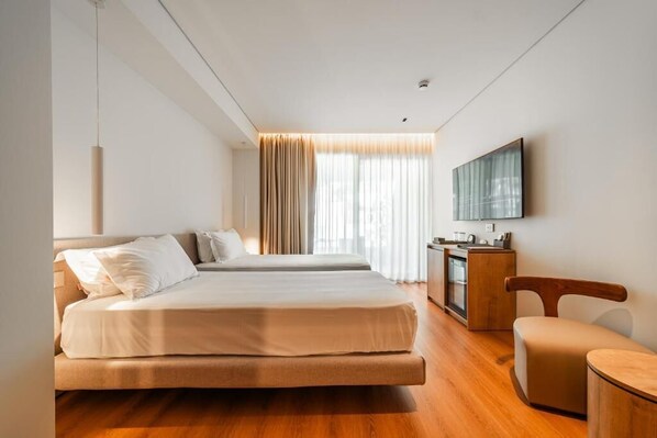 A hotel room with two beds, a desk, a chair, and a TV mounted on the wall. - Hotel Vale (Sarande)