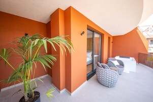 A balcony with a potted plant, wicker furniture, and a sliding glass door.