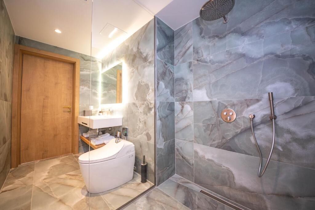 A modern bathroom with a toilet, sink, and shower.