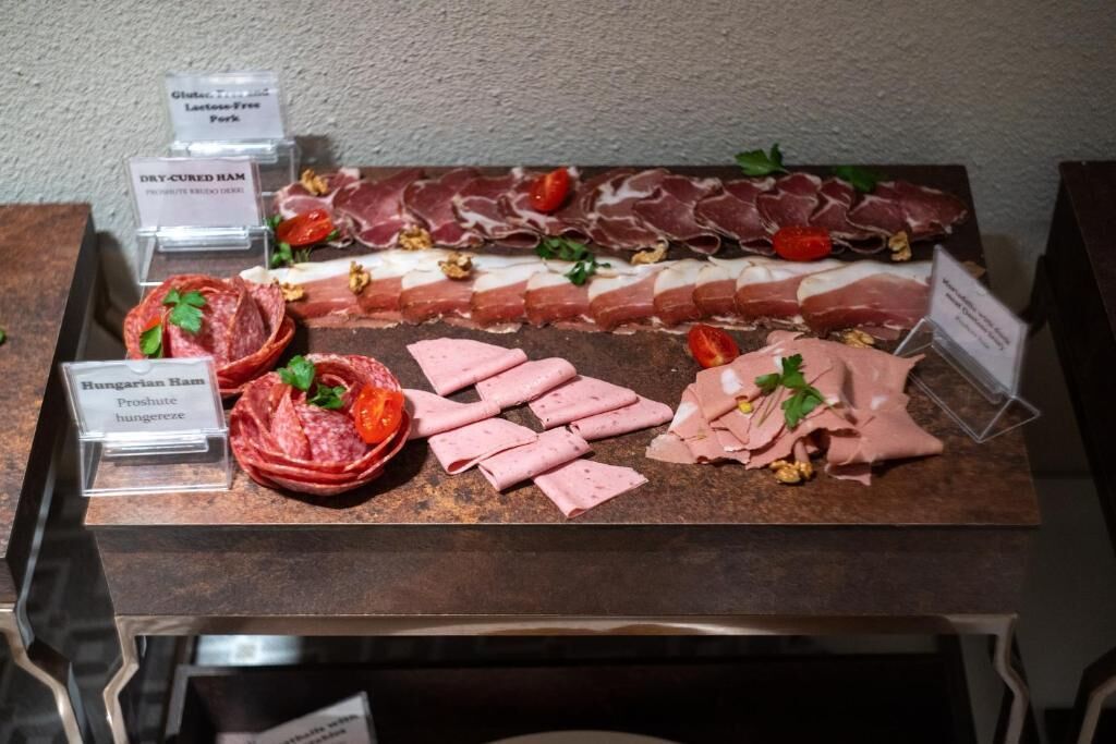 A selection of cured meats including Hungarian Ham and Dry-Cured Ham, arranged on a display counter.
