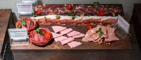 A selection of cured meats including Hungarian Ham and Dry-Cured Ham, arranged on a display counter.