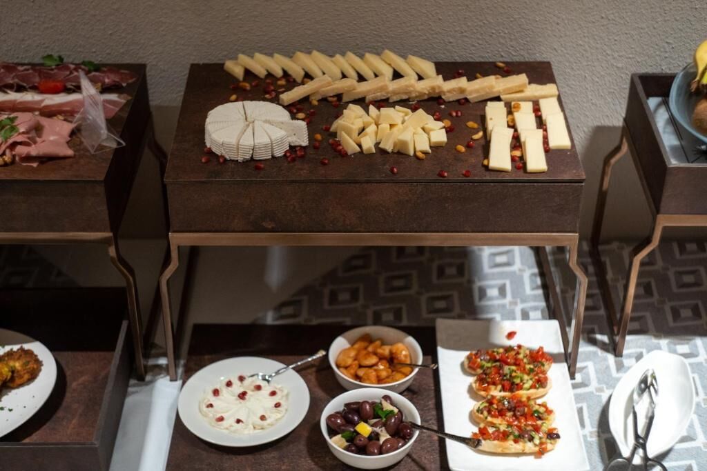 A buffet table with various food items including cheeses, meats, and vegetables.
