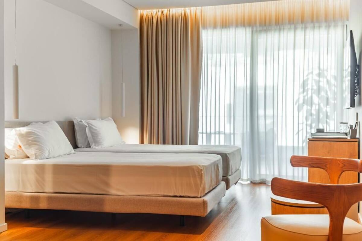 Una habitación de hotel con una cama, una silla, un escritorio y un televisor.