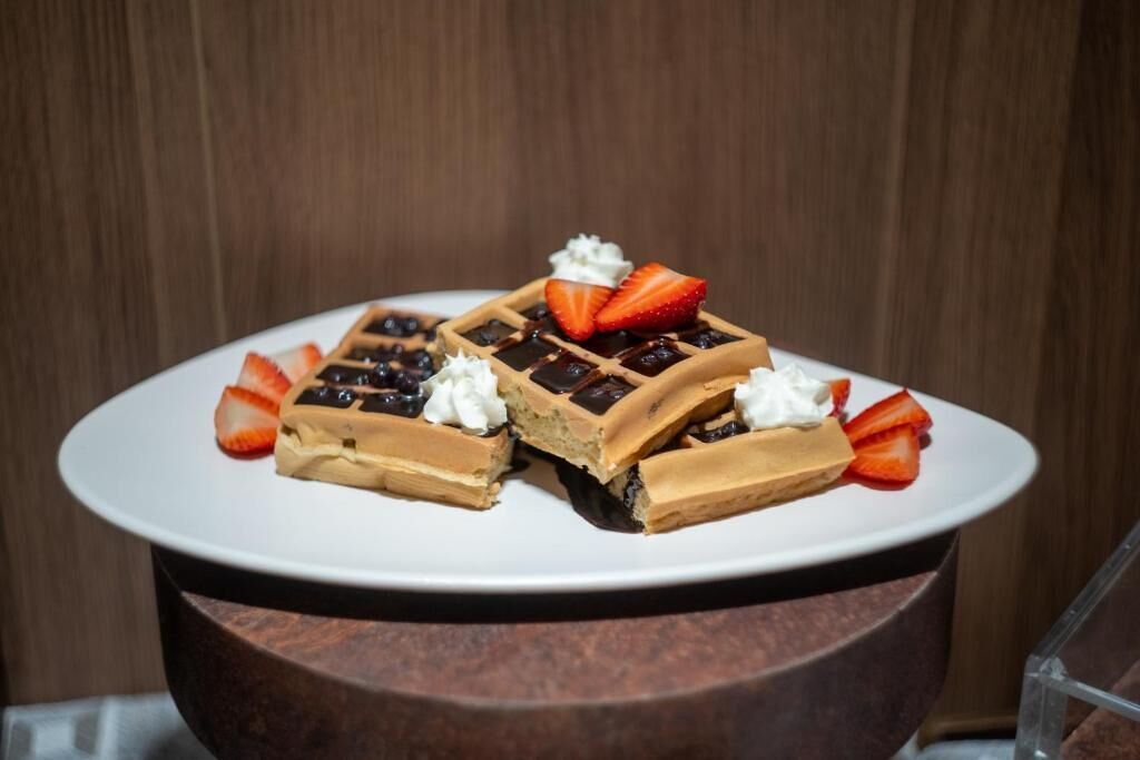 A plate of waffles with whipped cream and strawberries.