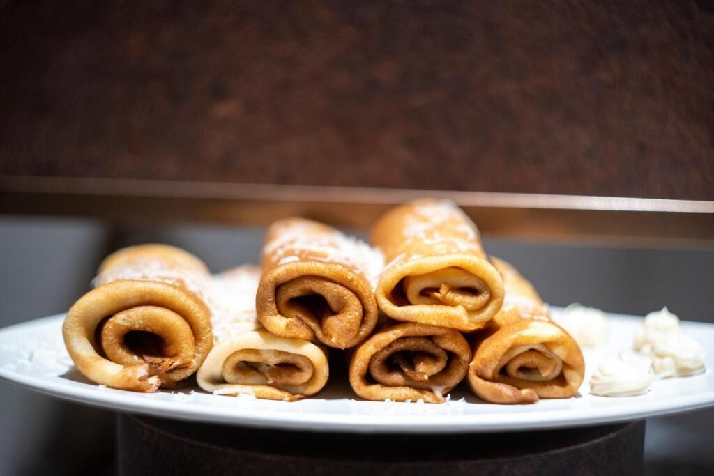 A plate of rolled pastries with powdered sugar.