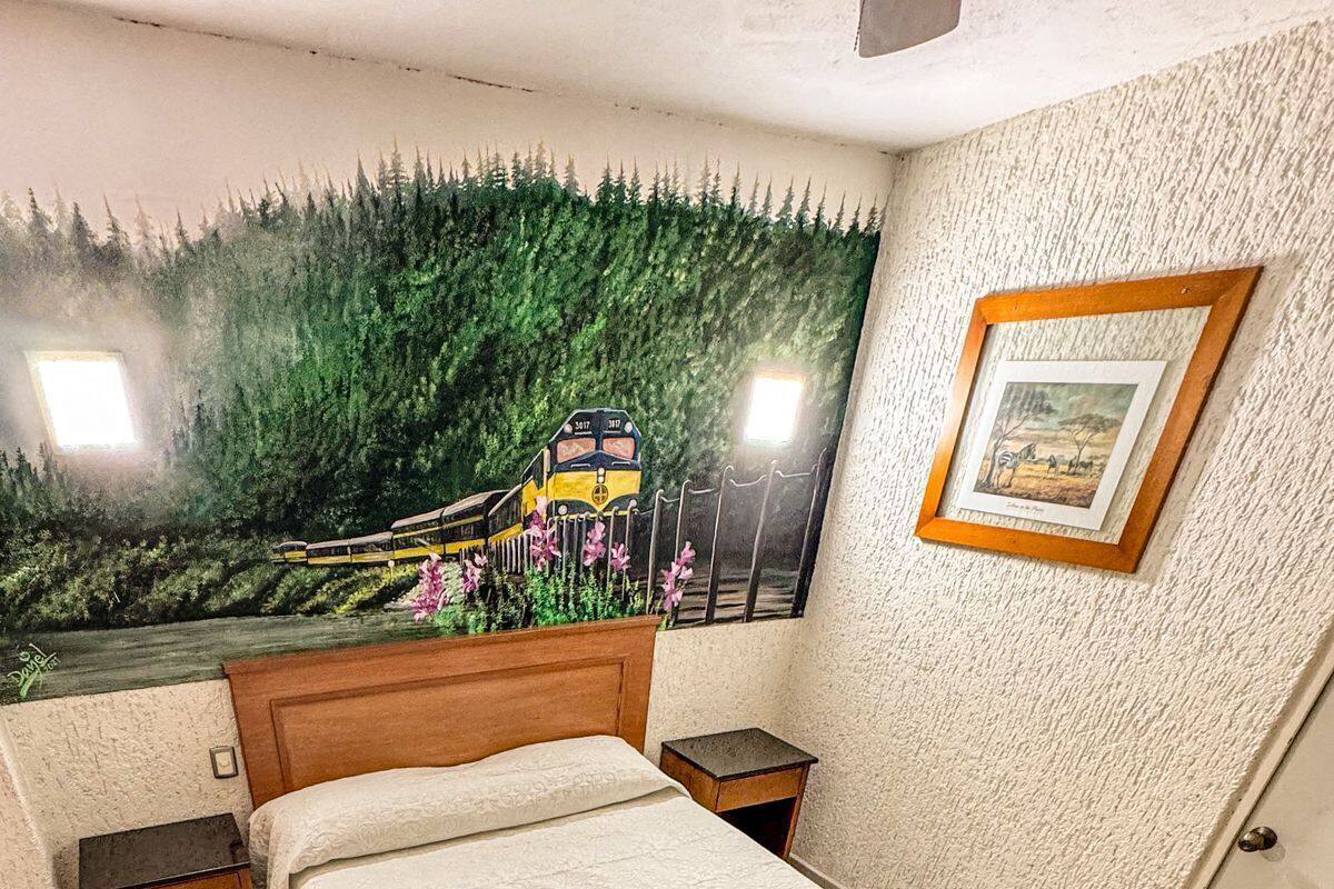 A bedroom with a bed, nightstands, a mural, and a framed picture on the wall.