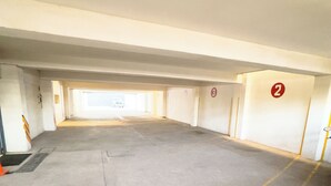 Un parking souterrain avec des planchers en béton, des emplacements de stationnement délimités et des murs numérotés indiquant les numéros des places de stationnement.