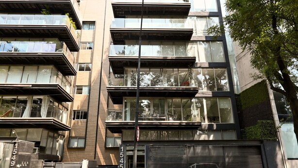 A multi-story building with balconies, large windows, and a closed garage door. - Luxury Penthouse in Polanco | Private Terraces + Prime Location (Ciudad de México)