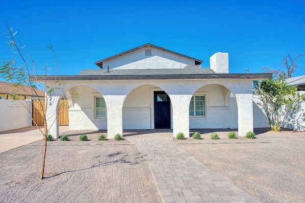 A single-story house with a central entrance, arched windows, and a chimney.