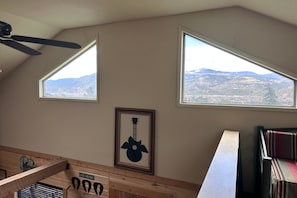 A room with a sloped ceiling, two windows with a mountain view, a framed guitar artwork, and a sign that says 'Live Music'. - Mountain Soul | ATV Access, Porch & Mountain Views (South Fork)