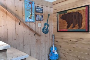 A wooden wall with a guitar, a bear silhouette, and several signs including one that says 'DO YOUR OWN TUNING.' - Mountain Soul | ATV Access, Porch & Mountain Views (South Fork)