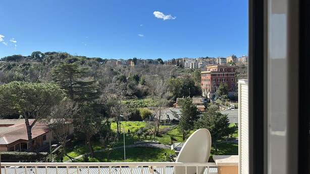 Un balcon donnant sur un quartier résidentiel, avec vue sur des maisons et des arbres.