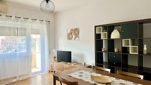 Un coin repas avec une table en bois, des chaises, un téléviseur et une bibliothèque.